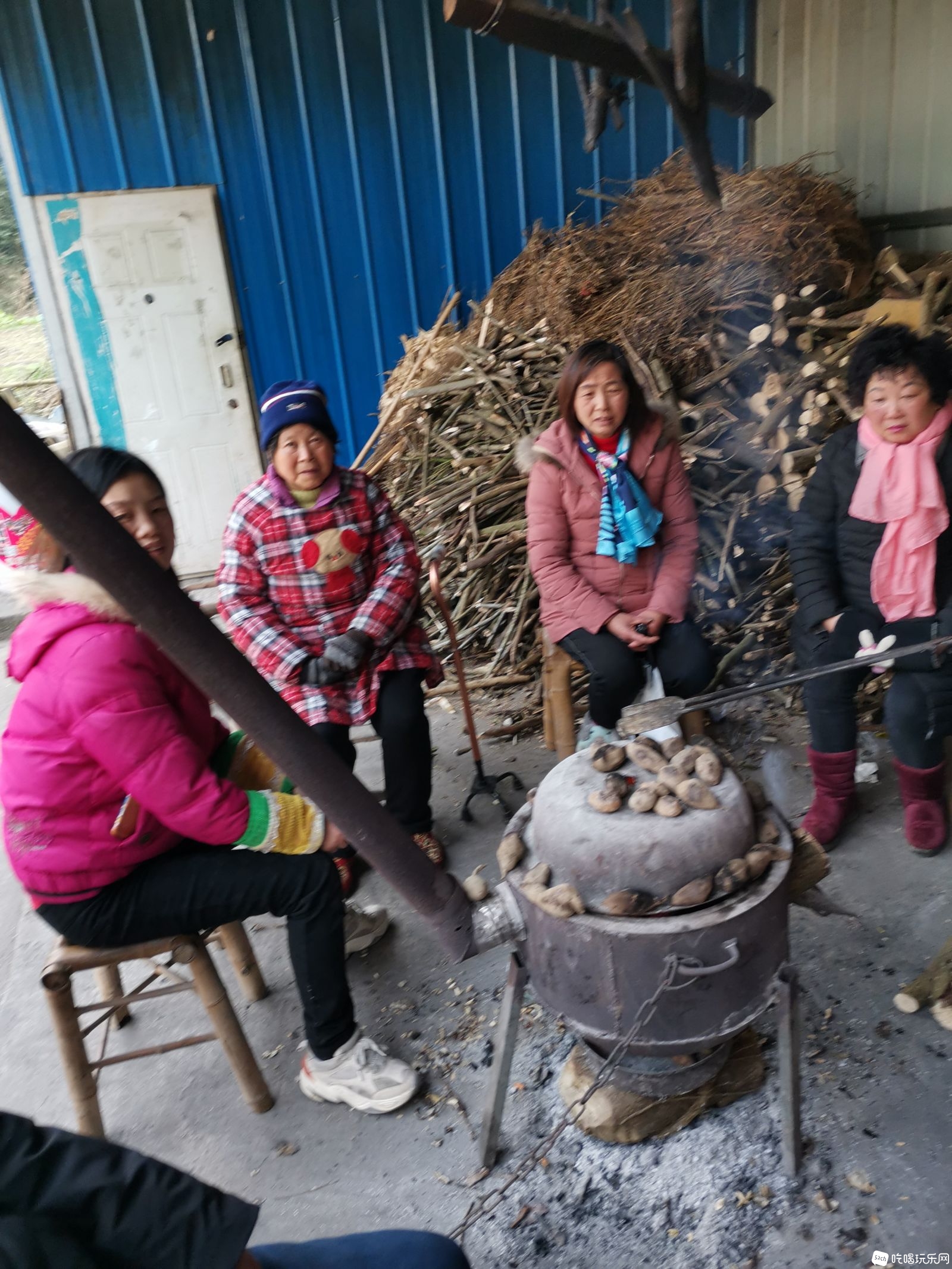 村民围坐在火炉旁，聊天，烤着红薯，土豆